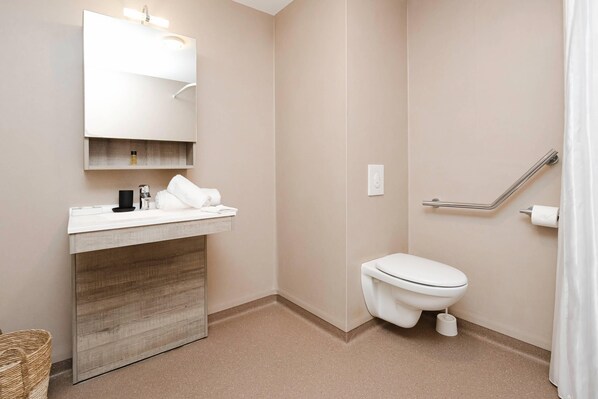 Une salle de bain moderne avec un lavabo, un miroir et des toilettes, le tout de couleur blanche.