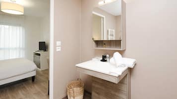 Una habitación de hotel moderna con una cama, un lavamanos blanco, un espejo y un armario de madera.