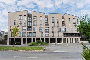 Un immeuble à plusieurs étages doté d’une architecture moderne, caractérisé par une série de balcons et de grandes fenêtres.