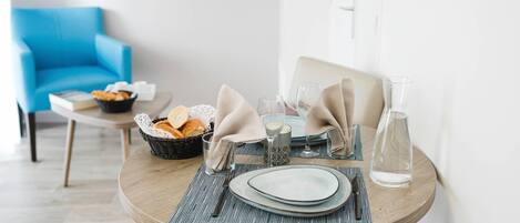 A dining table set with plates, cutlery, glasses, and a basket of bread.