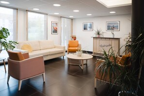 Un lobby moderno con un sofá, sillones, una mesa de centro y una chimenea.