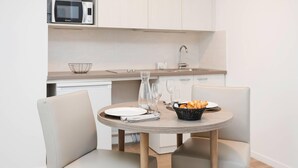 Een compacte keuken met een magnetron, een spoelbak en een eethoek met een tafel voor twee personen.