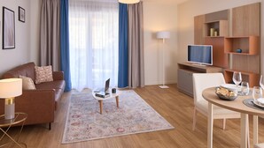 A modern living room with a sofa, coffee table, and dining area. - Quality Aparthotel Voiron (Voiron)
