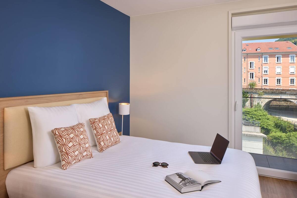 Ein Hotelzimmer mit einem Bett, einem Laptop und einem offenen Buch.
