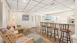 Una cocina moderna con barra, suelo de madera y vista al océano.