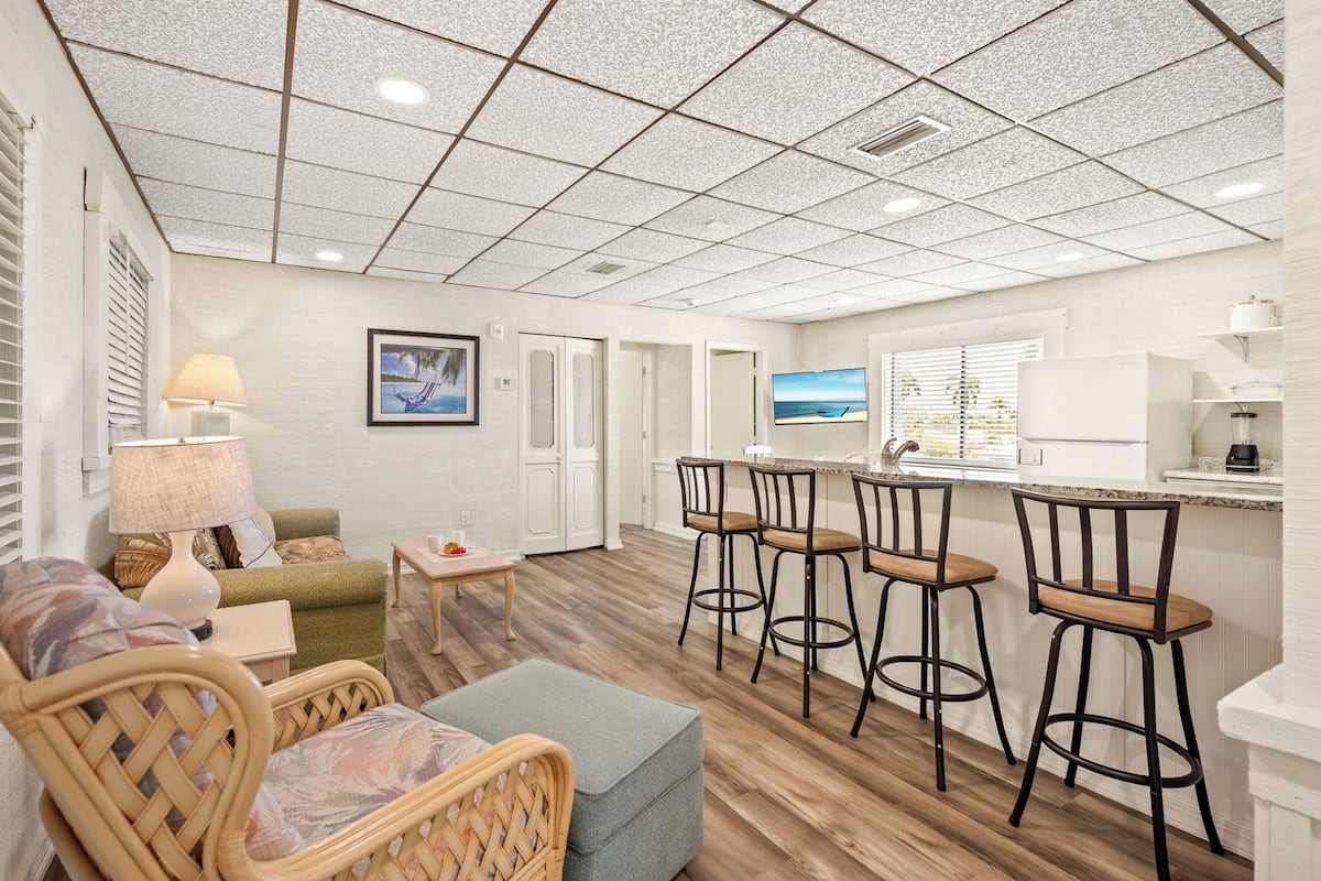 A modern kitchen with a bar area, wooden flooring, and a view of the ocean.