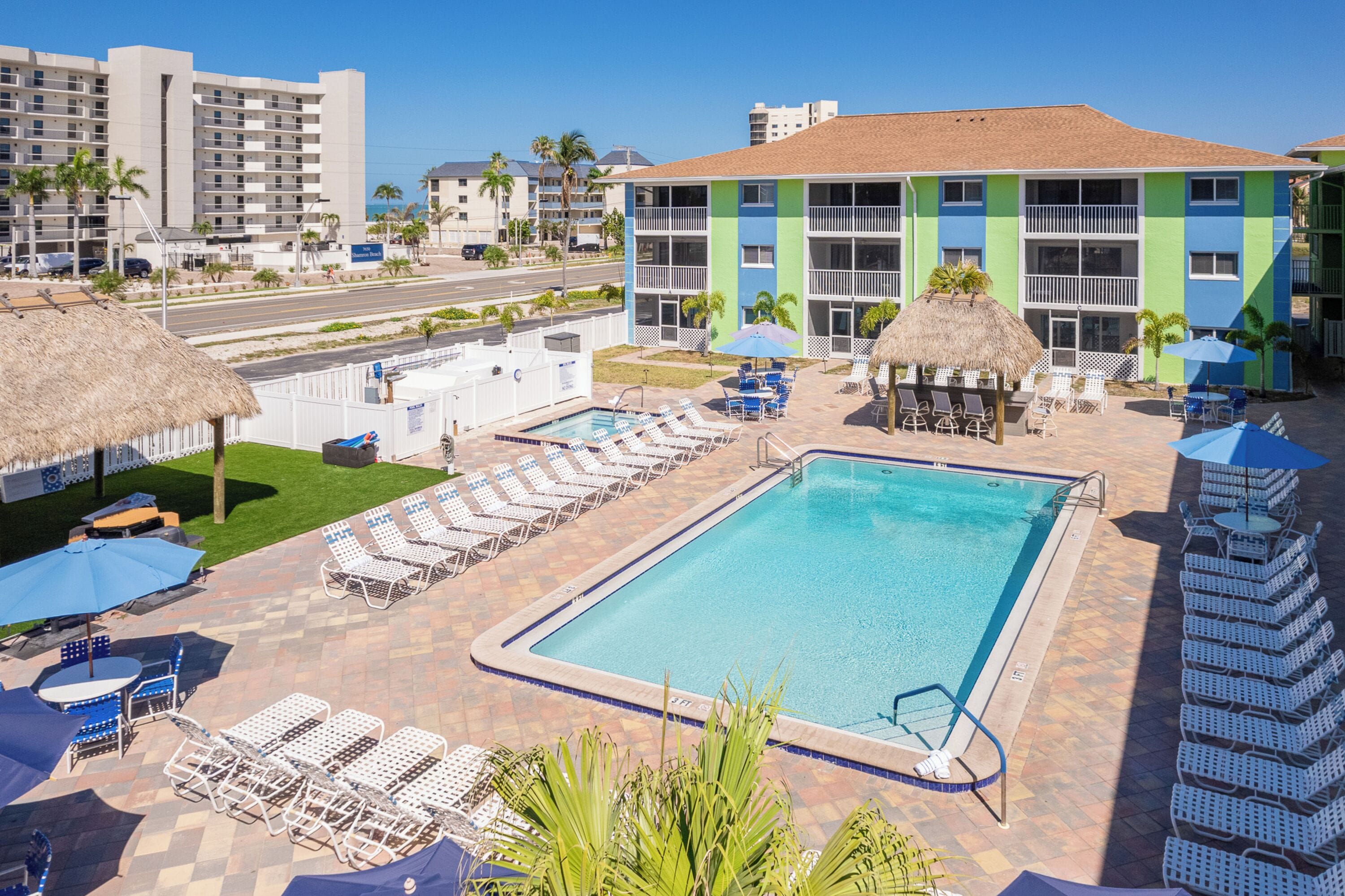 A hotel with a swimming pool, lounge chairs, and umbrellas.