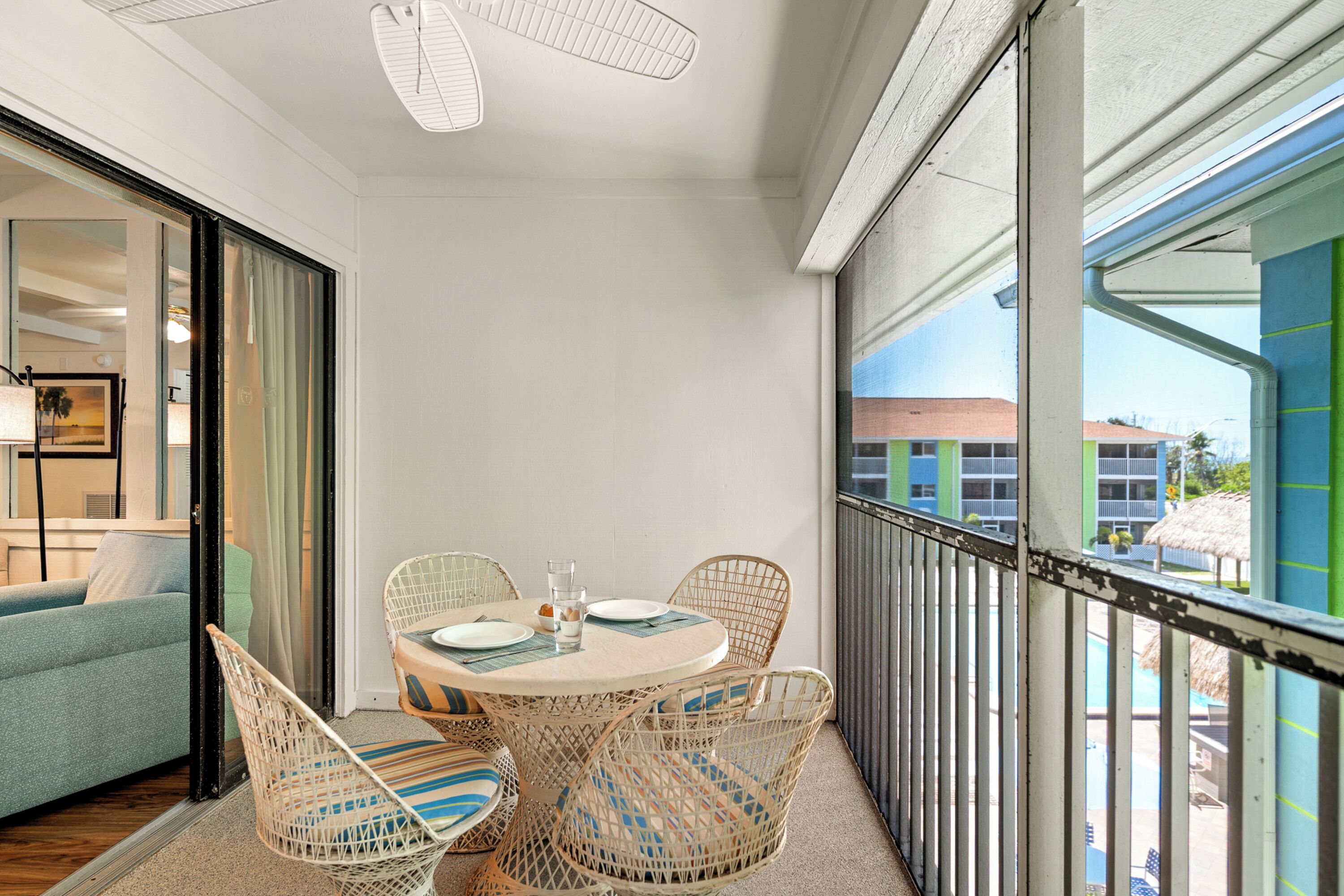 A balcony with wicker chairs, a round table, and a view of buildings.