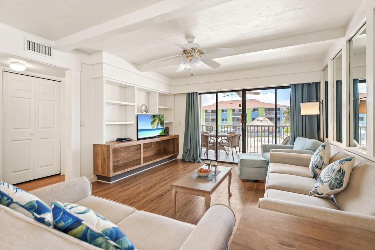 A modern living room with a television, sofa, coffee table, and a balcony with a view.