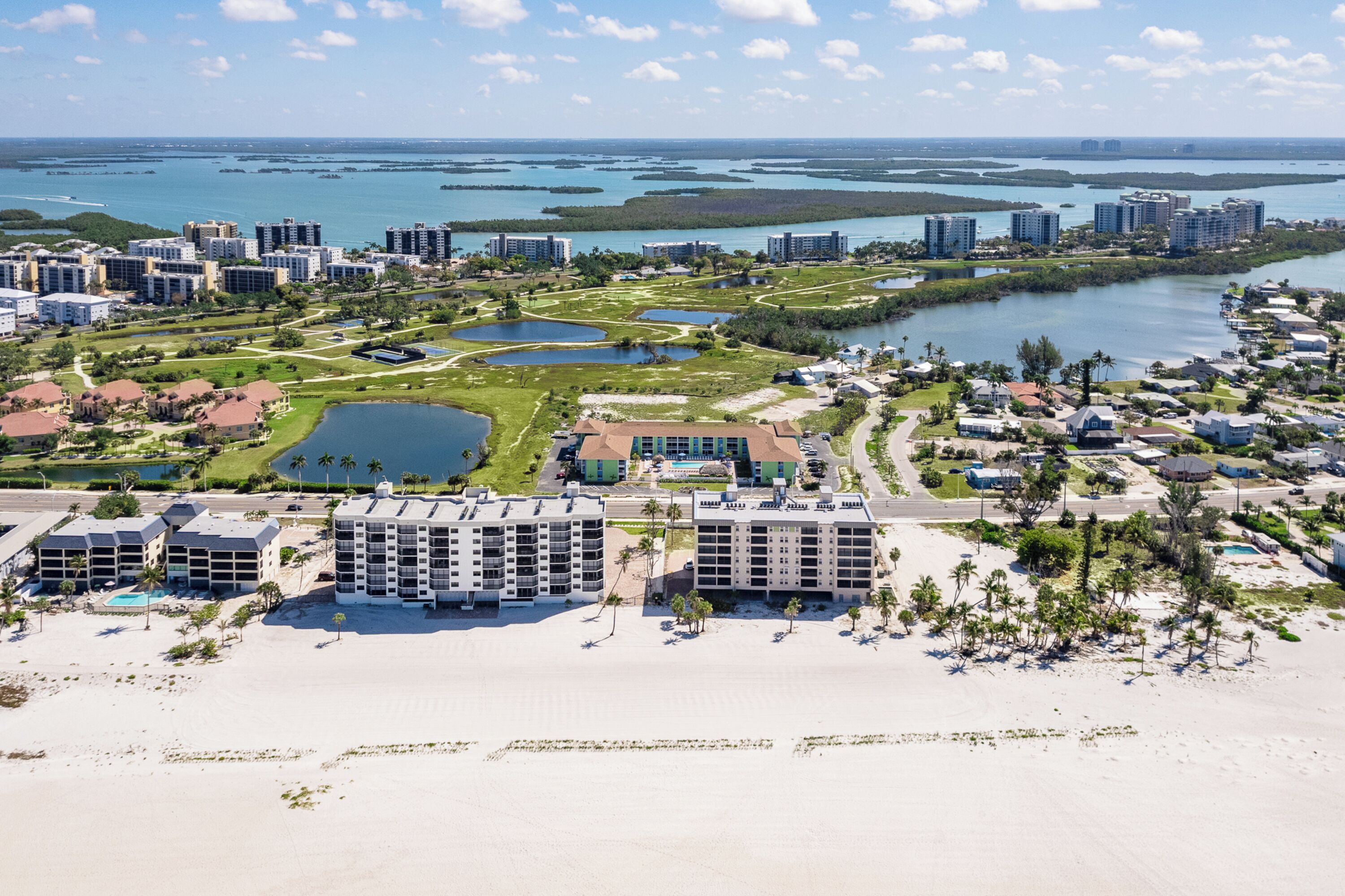 Un hôtel situé sur la côte, composé de plusieurs bâtiments, avec une plage et un port de plaisance.