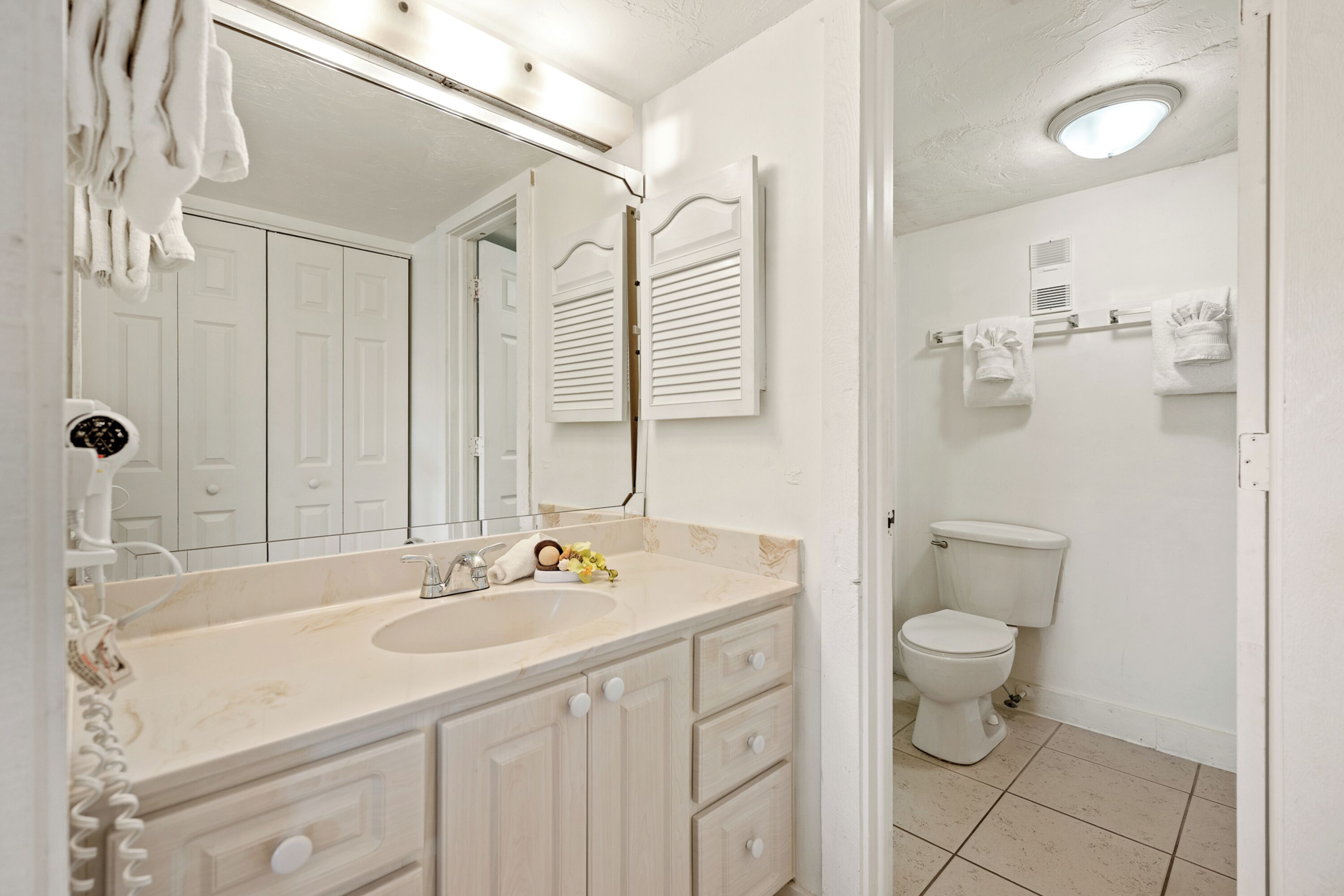 A bathroom with a sink, mirror, toilet, and towel rack.