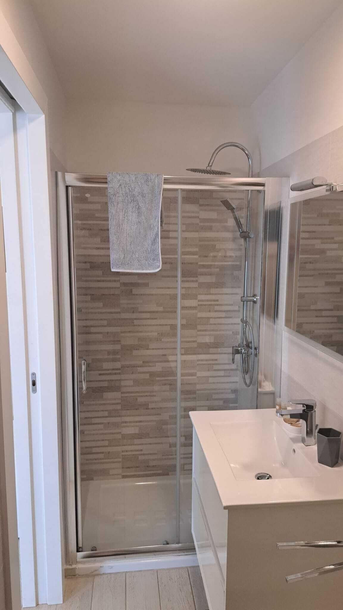 Un baño moderno con ducha de vidrio, un lavabo blanco y un espejo sobre él.