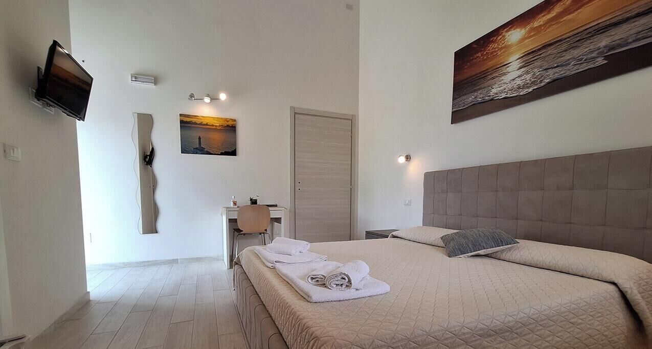 Une chambre d’hôtel avec un lit, un bureau, une chaise, une télévision et un tableau au mur.