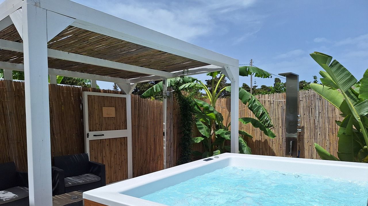 Piscina rectangular con muelle de madera y una estructura de pérgola blanca.