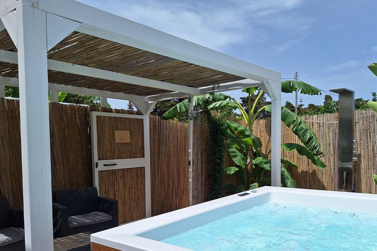 A rectangular swimming pool with a wooden deck and a white pergola structure.