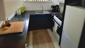 Una cucina compatta con finestra, lavello, fornello e frigorifero.