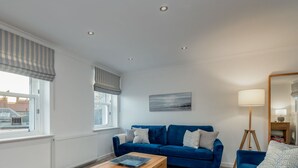 En moderne stue med en blå sofa, et sofabord og en gulvlampe.