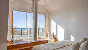 A bedroom with a large window, a bed, and a view of the outdoors. - East Bay 7BR Luxury Home, Beach, Dock, Hot-tub! (Williamsburg)