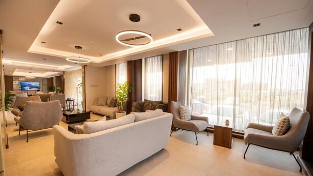A modern living room with a sofa, armchairs, and a TV. - Golden Rose Hotel (Jizan)