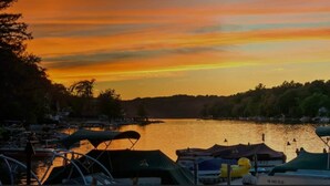 Un port de plaisance avec des bateaux amarrés, un lac paisible et un coucher de soleil en arrière-plan.