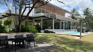 Een modern huis met een zwembad, overdekt terras en een zitgedeelte buiten.