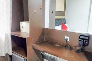 A hotel room with a wooden desk, a chair, a small white cabinet, a mirror, and a red object on the windowsill. - Red Velvet Inn Bukit Bintang (Kuala Lumpur)
