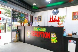 A reception area with a reception desk, a clock, framed pictures, and a 'No Entry' sign. - Red Velvet Inn Bukit Bintang (Kuala Lumpur)