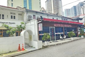 A Red Velvet Inn Hotel with a red awning, outdoor seating, and a white wall with a sign for Elephant Republic. - Red Velvet Inn Bukit Bintang (Kuala Lumpur)