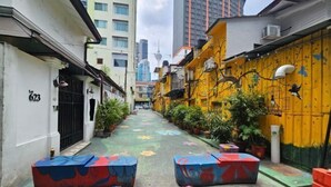 A narrow alleyway with colorful murals and potted plants, leading to a building with a number 623 sign. - Red Velvet Inn Bukit Bintang (Kuala Lumpur)