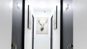 A hallway with two doors on either side, a framed deer head artwork on the wall, and a light-colored floor. - Red Velvet Inn Bukit Bintang (Kuala Lumpur)