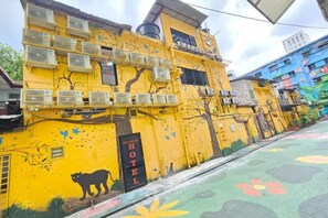 A yellow building with a 'HOTEL' sign, air conditioning units, and a tree mural. - Red Velvet Inn Bukit Bintang (Kuala Lumpur)