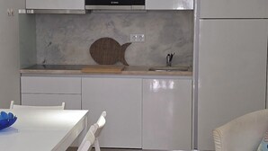 Uma cozinha compacta com armários brancos, um micro-ondas Bosch e um painel de fundo em formato de peixe.