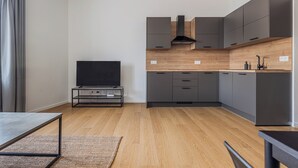 Une cuisine moderne avec des meubles gris, un plan de travail en bois et une hotte intégrée.