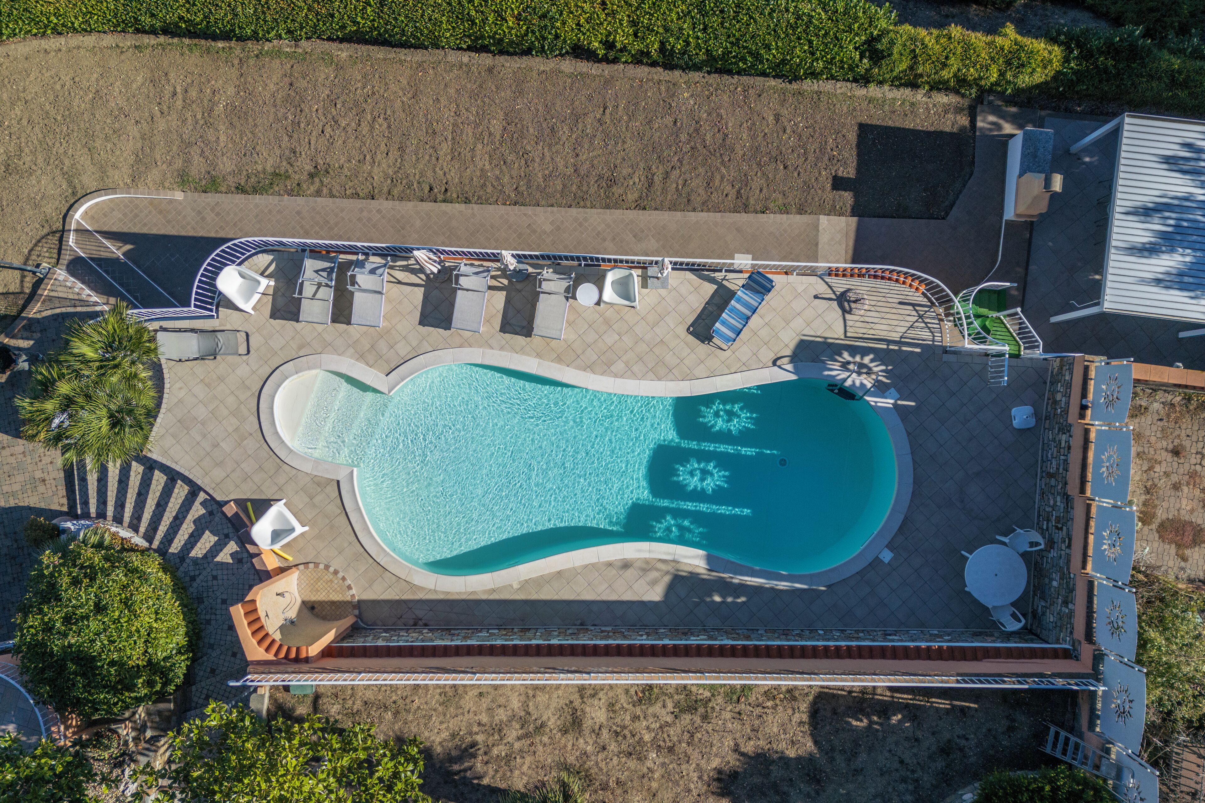 Vue aérienne d’une piscine avec des chaises longues et un cadran solaire.