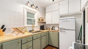 A kitchen with a white refrigerator, a sink, and a wooden countertop. - Omaha Escape Central Getaway with Private Sauna! (Omaha)