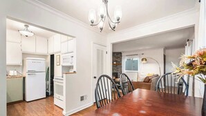A modern kitchen with white cabinetry, a wooden dining table, and a chandelier. - Omaha Escape Central Getaway with Private Sauna! (Omaha)