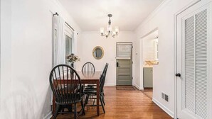 A dining area with a wooden table and chairs, a chandelier, and a mirror on the wall. - Omaha Escape Central Getaway with Private Sauna! (Omaha)