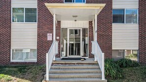 Un edificio de ladrillo de dos pisos con un acceso cubierto y una escalera.