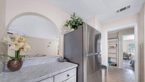 A modern kitchen with white cabinetry, a stainless steel refrigerator, and a marble countertop. - Modern 5BR Home |Cozy Fireplace, Office & Downtown (Austin)