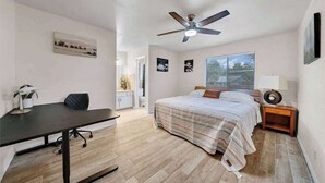A bedroom with a bed, a desk, a ceiling fan, and a window with blinds. - Modern 5BR Home |Cozy Fireplace, Office & Downtown (Austin)
