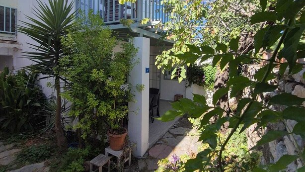 A courtyard with a white building, stone pathway, and various plants. - Serene building with AC in beautiful Bodrum (Bodrum)