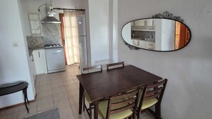 A dining area with a wooden table and chairs, a ceiling fan, a kitchen visible through an open doorway, and a wall-mounted mirror. - Serene building with AC in beautiful Bodrum (Bodrum)