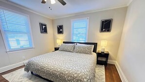 A bedroom with a bed, two bedside tables, a ceiling fan, and two windows with blinds. - Hidden Getaway | Fire Pit | 1K,2Q/1 bath (Eden)