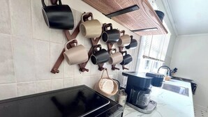 A kitchen with a coffee maker, a microwave, and a set of hanging mugs. - Hidden Getaway | Fire Pit | 1K,2Q/1 bath (Eden)