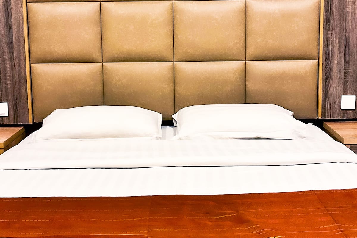 A bed with a tufted headboard, white bedding, and a wooden floor.