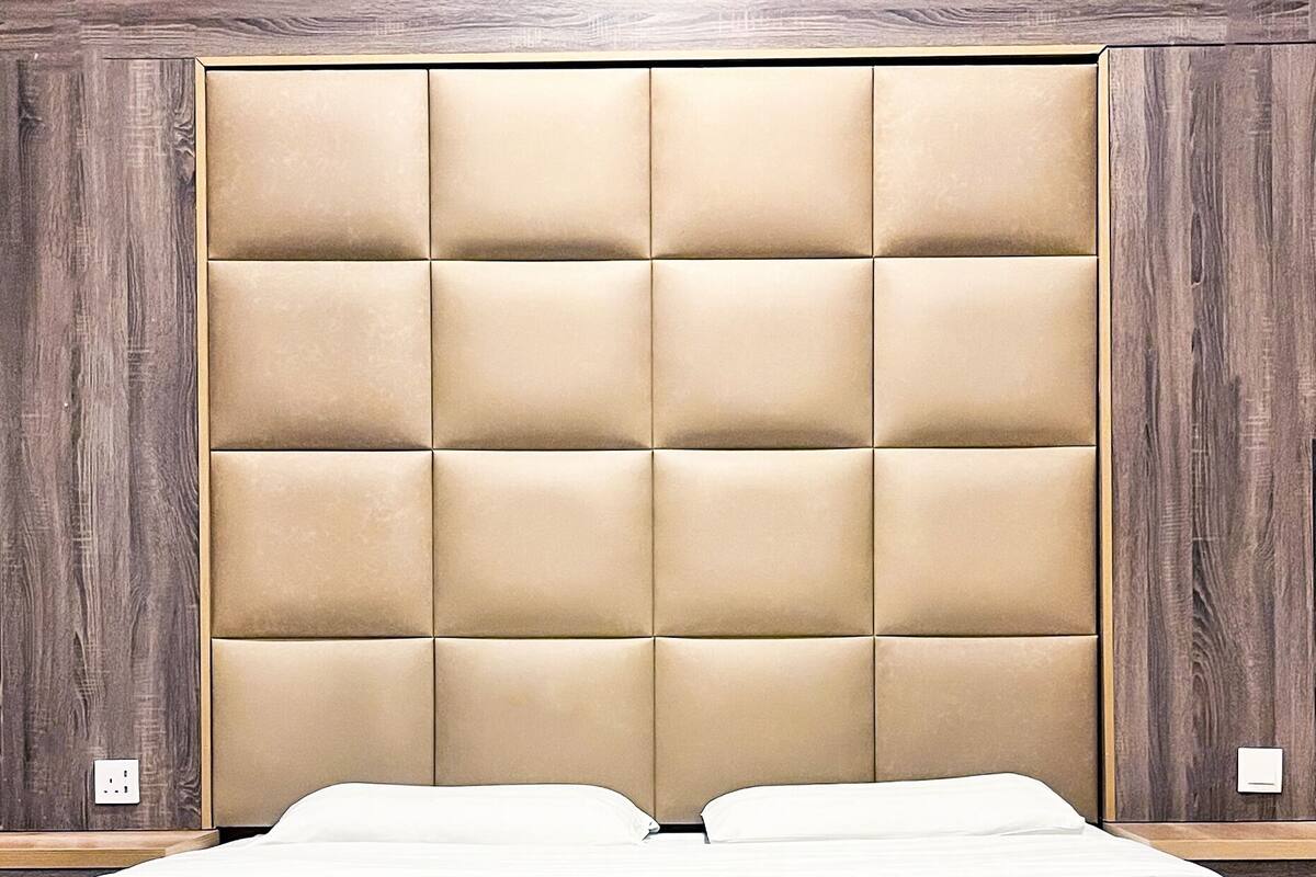A bed with a headboard, a red accent, and a wooden wall.