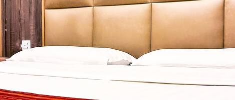 A bed with a tufted headboard, white bedding, and a red patterned carpet.