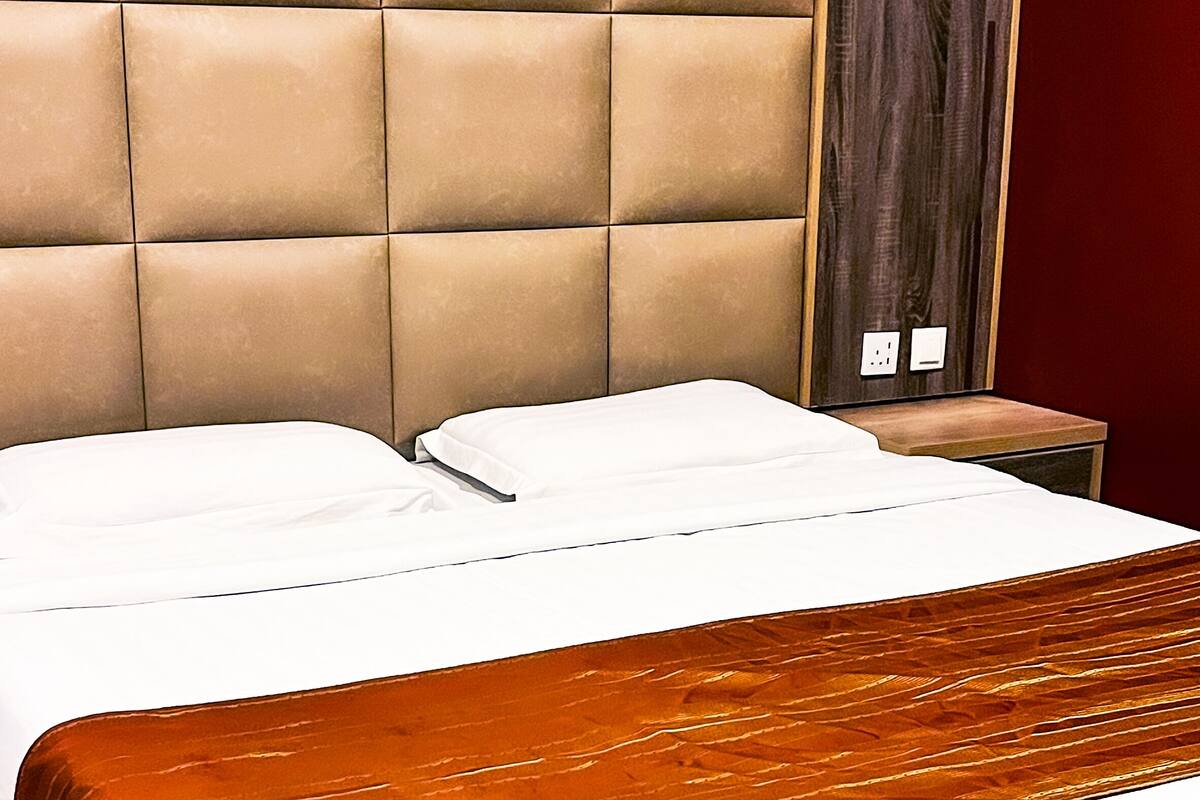 A bed with a tufted headboard, a wooden nightstand, and a red wall.