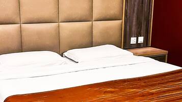 A bed with a tufted headboard, a wooden nightstand, and a red wall.