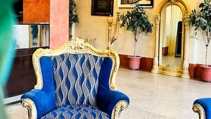 A grand lobby with ornate blue and gold chairs, a large mirror, and framed artwork on the walls. - Alora Zone (Abha)